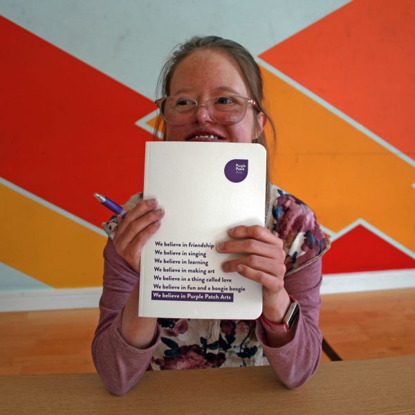 A photo of a participant holding the Purple Patch notebook